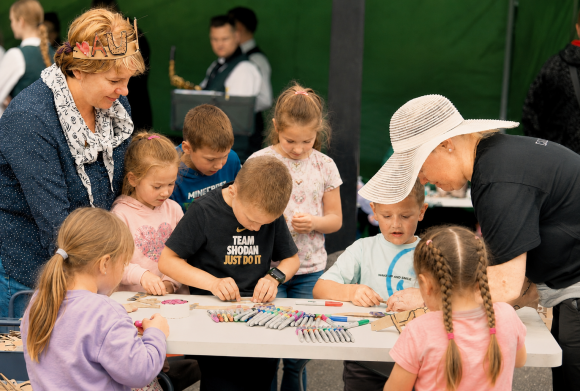 Aušra ir Dalia padeda pasidaryti karūną Bibliotekos veiklos „Vaikų kieme“ Platelių vasaros šventėje